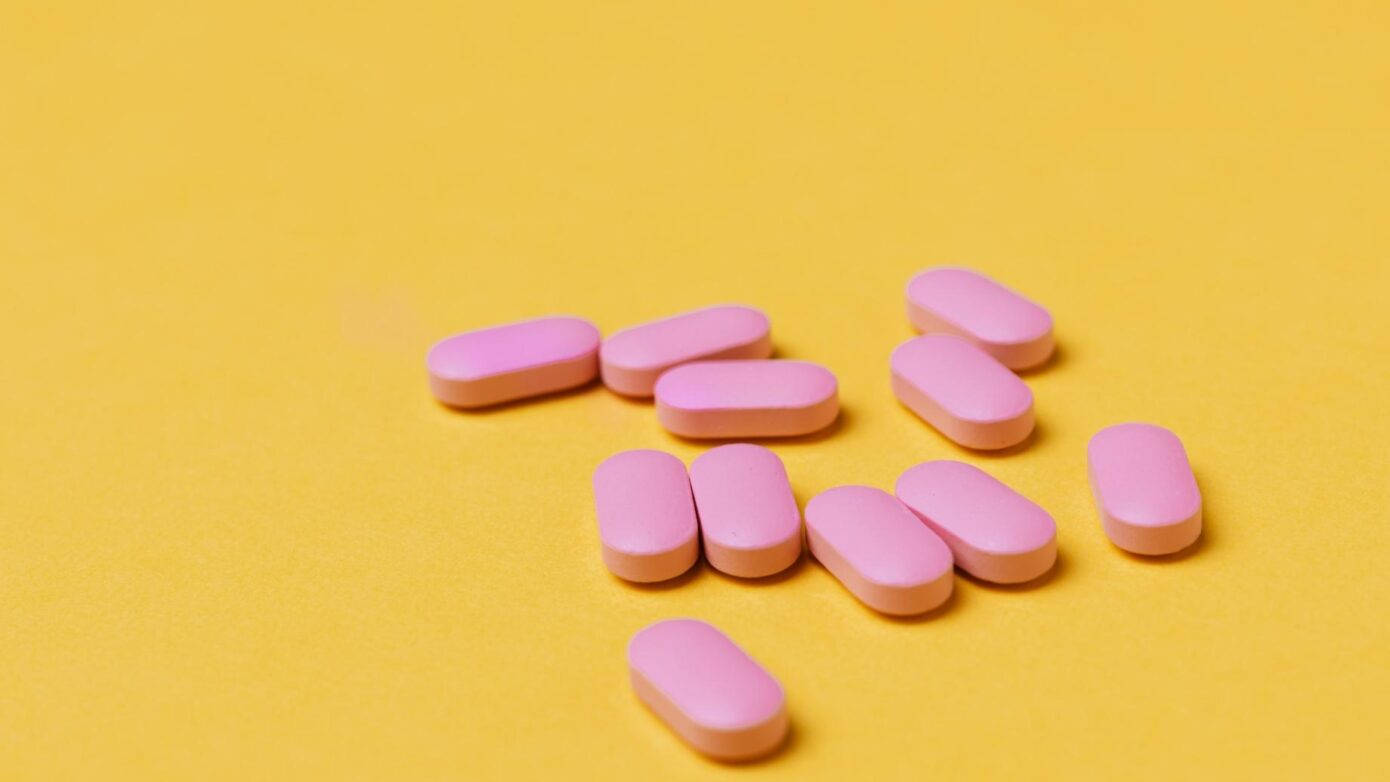 pink pills against a yellow background