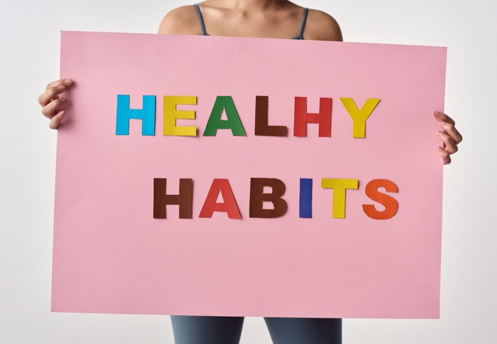 Woman holding sign saying healthy habits in coloured letters