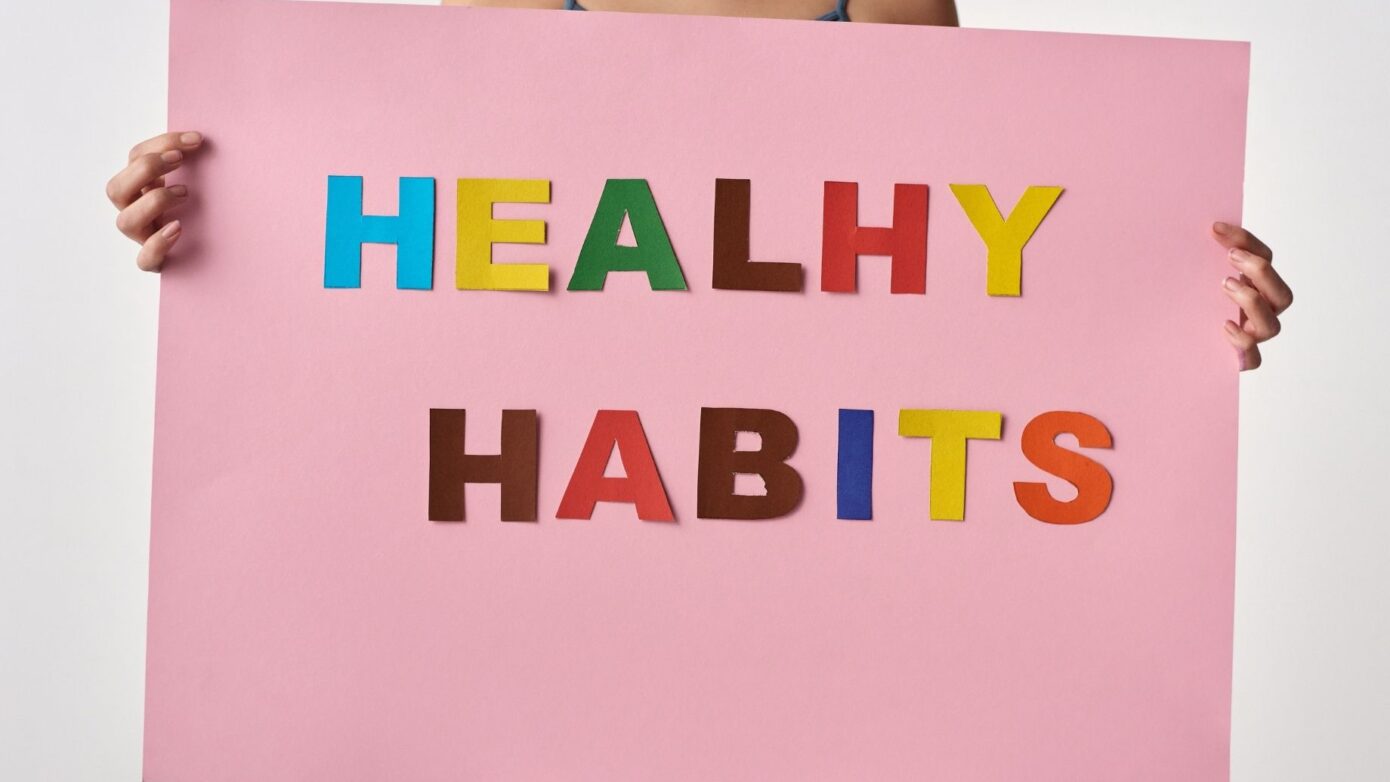 Woman holding sign saying healthy habits in coloured letters