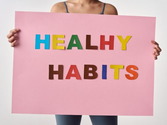 Woman holding sign saying healthy habits in coloured letters